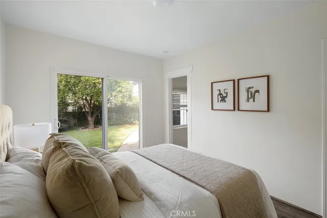 a view of a white house next to a yard with a large tree