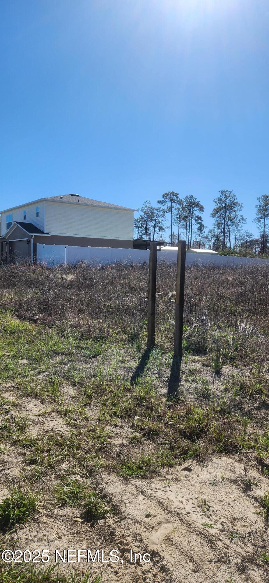 a view of a dry yard with wooden fence