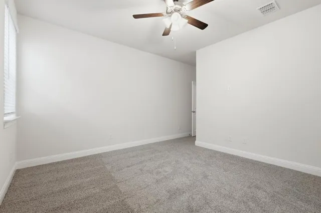 an empty room with a window and a fan