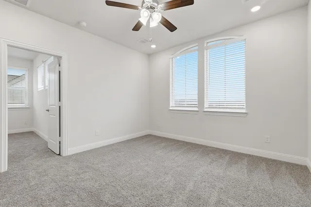 an empty room with chandelier fan and windows