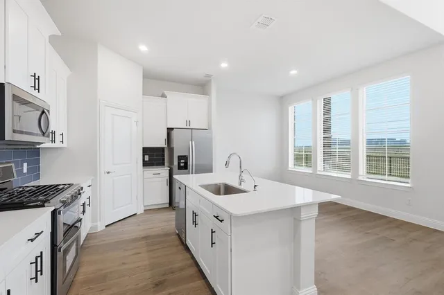 a kitchen that has a sink a stove and cabinets