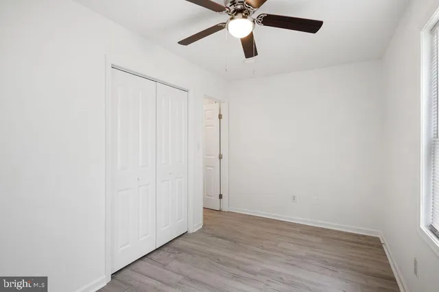 an empty room with wooden floor closet and fan