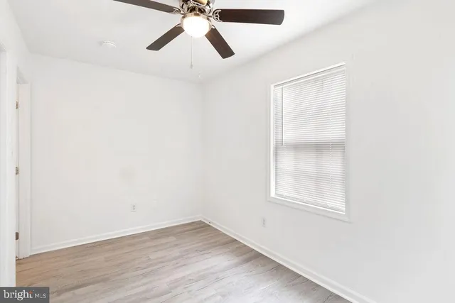 an empty room with a window and a fan