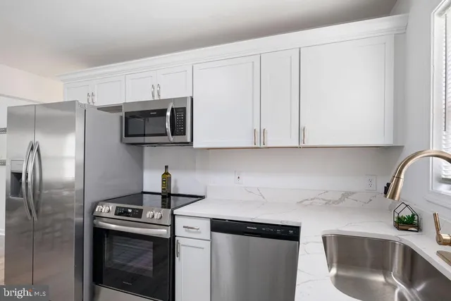 a kitchen with stainless steel appliances granite countertop a sink a stove a microwave and refrigerator