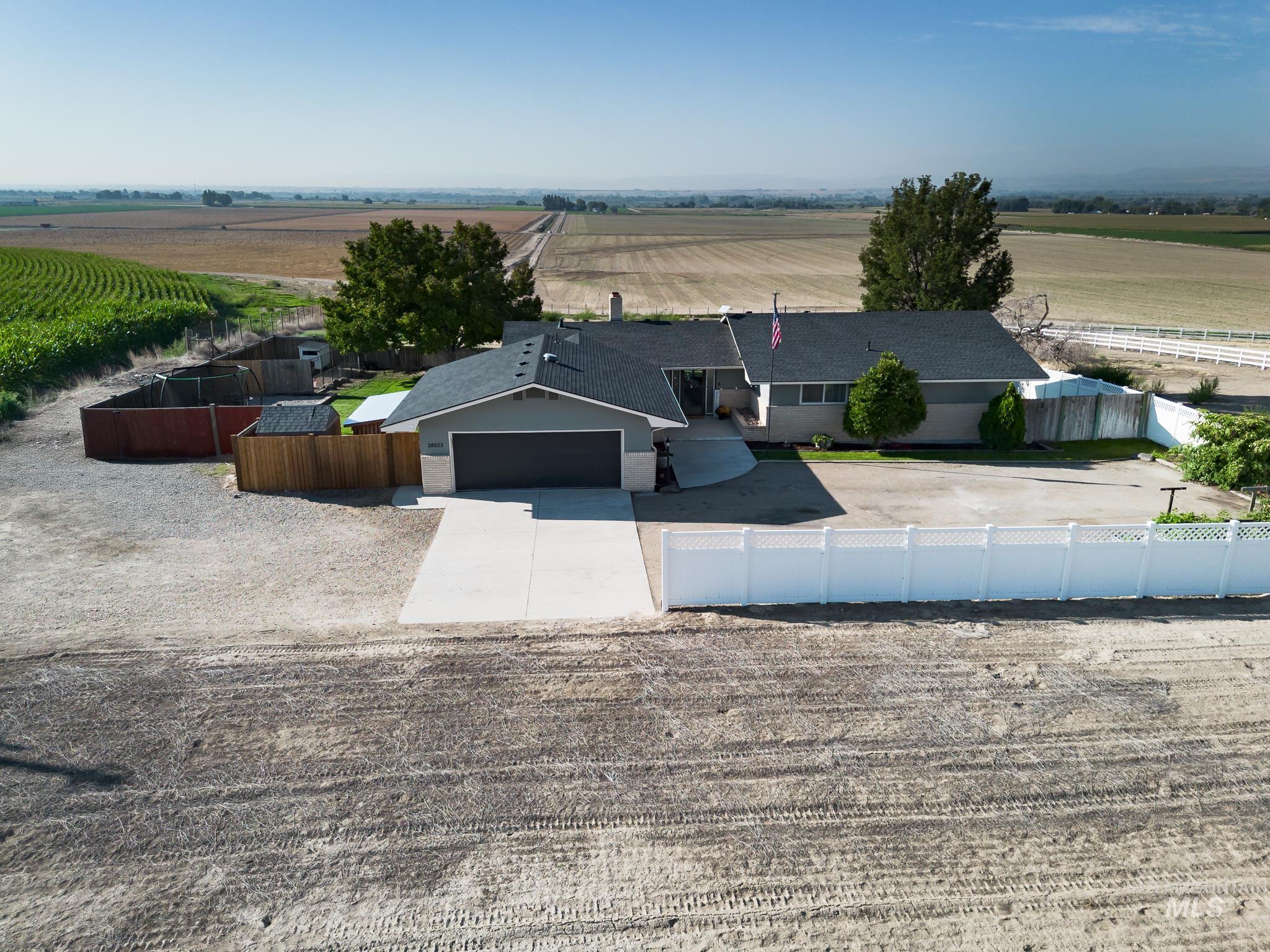 28503 Old Fort Boise Road Parma, ID 83660 - Photo 1 of 1 View of front of house with a rural view, a fenced front yard, driveway, agricultural plots, and a garage