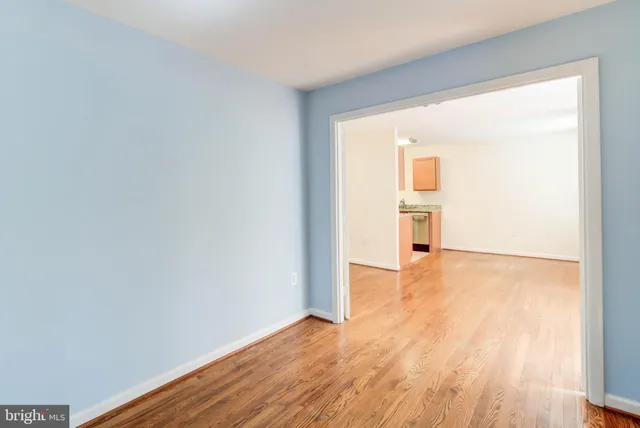 a view of empty room with wooden floor and a window