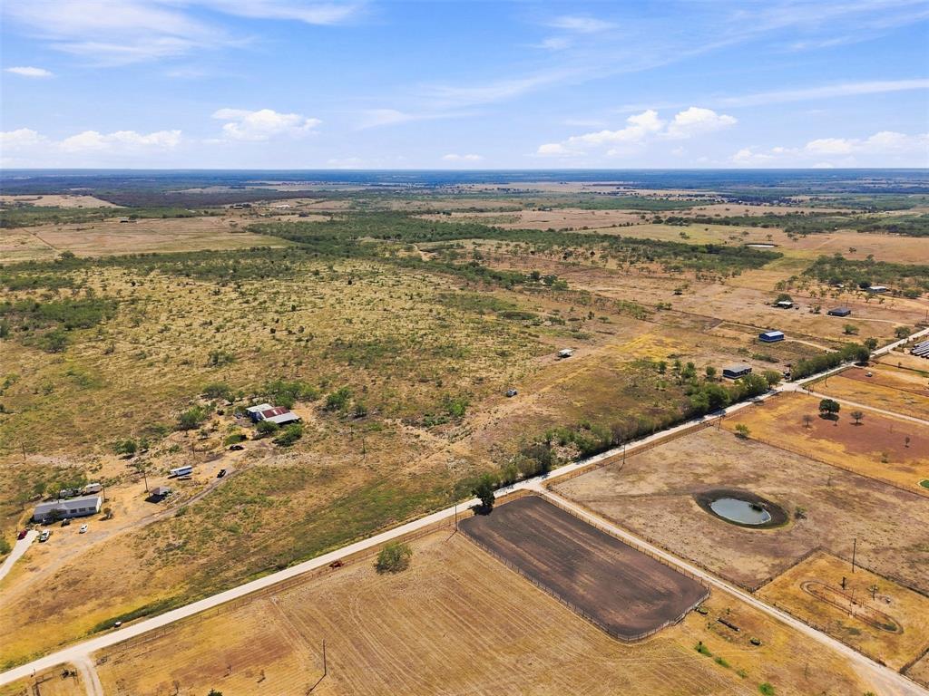 3208 Northeast County Road Powell, TX 75153 - Photo 29 of 29 Expansive rural landscape featuring a pond, cultivated fields, and scattered residential structures