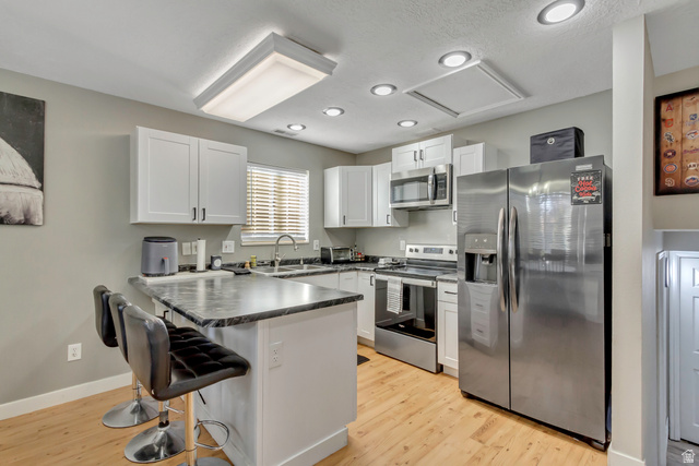 933 South Freedom Boulevard, Unit 7 Provo, UT 84601 - Photo 1 of 23 Kitchen with stainless steel appliances, a peninsula, dark countertops, a breakfast bar area, and white cabinets