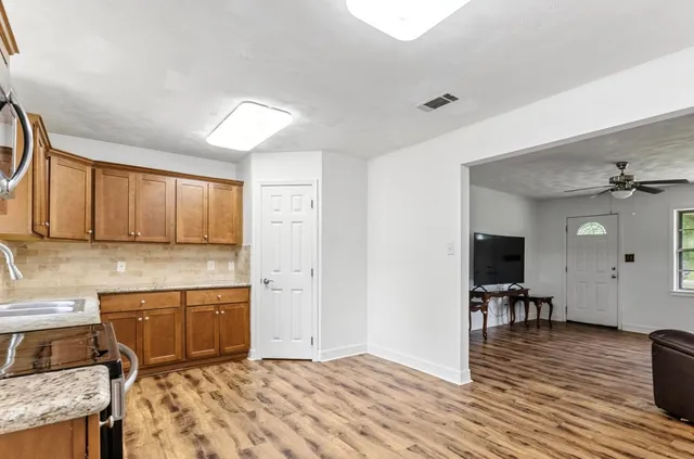 a kitchen with granite countertop a stove cabinets and wooden floor