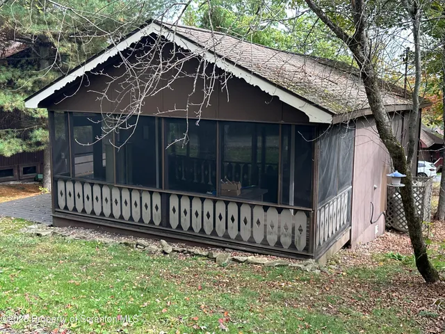 a view of a small house with wooden deck and furniture