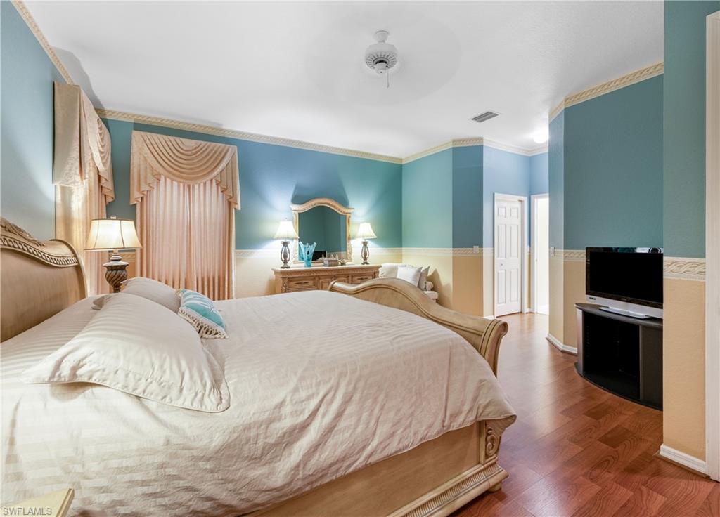 3641 Periwinkle Way Naples, FL 34114 - Photo 27 of 45 a large bedroom with a bed and wooden floor