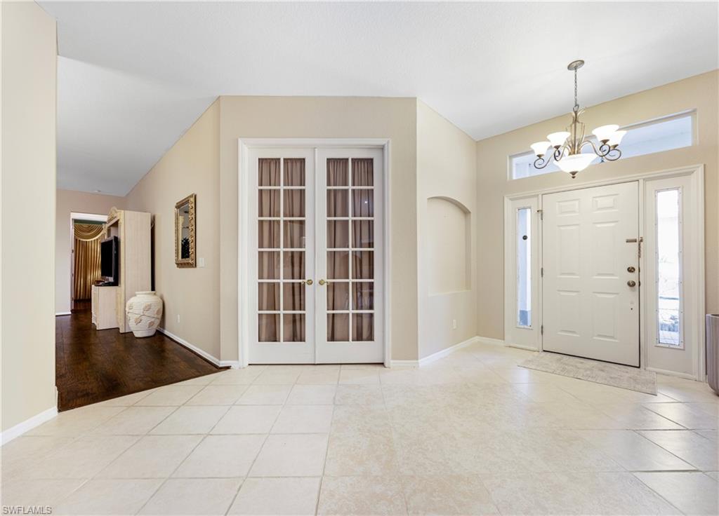 3641 Periwinkle Way Naples, FL 34114 - Photo 7 of 45 a view of an empty room with wooden floor and a kitchen