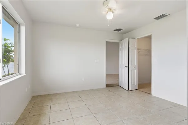 an empty room with a chandelier fan and windows