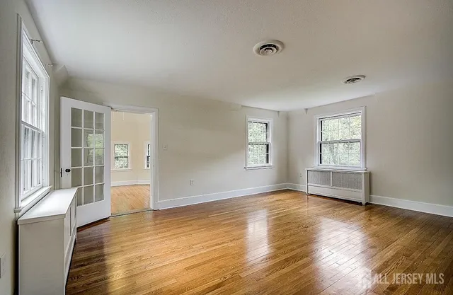 an empty room with wooden floor and windows