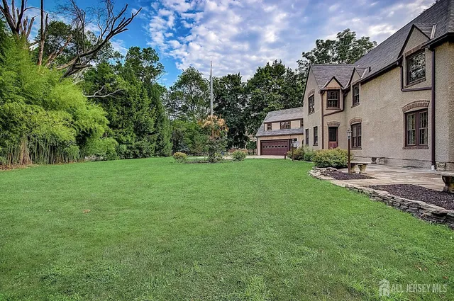 a front view of a house with garden and trees