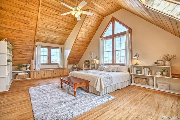 a spacious bedroom with a large bed a chandelier and windows