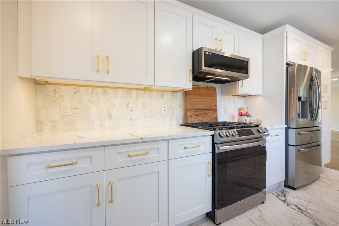 32887 Cedar Road Mayfield Heights, OH 44124 - Photo 10 of 44 Kitchen featuring backsplash, white cabinets, light stone countertops, light tile floors, and stainless steel appliances