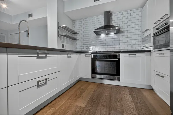 a large white kitchen with kitchen island a sink dishwasher a stove and a refrigerator with wooden floor