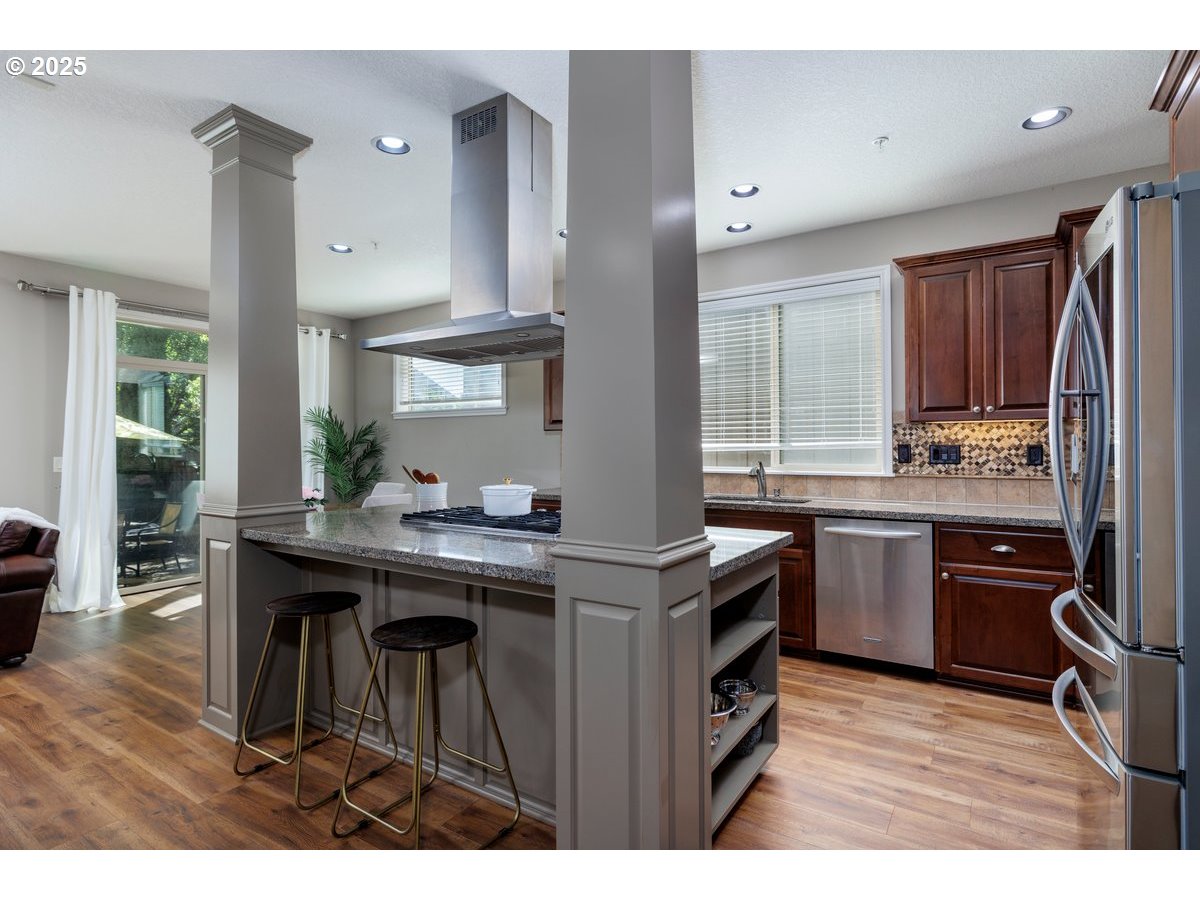 5598 Northwest 135th Avenue Portland, OR 97229 - Photo 13 of 45 a kitchen with kitchen island granite countertop wooden cabinets a stove a sink and a refrigerator