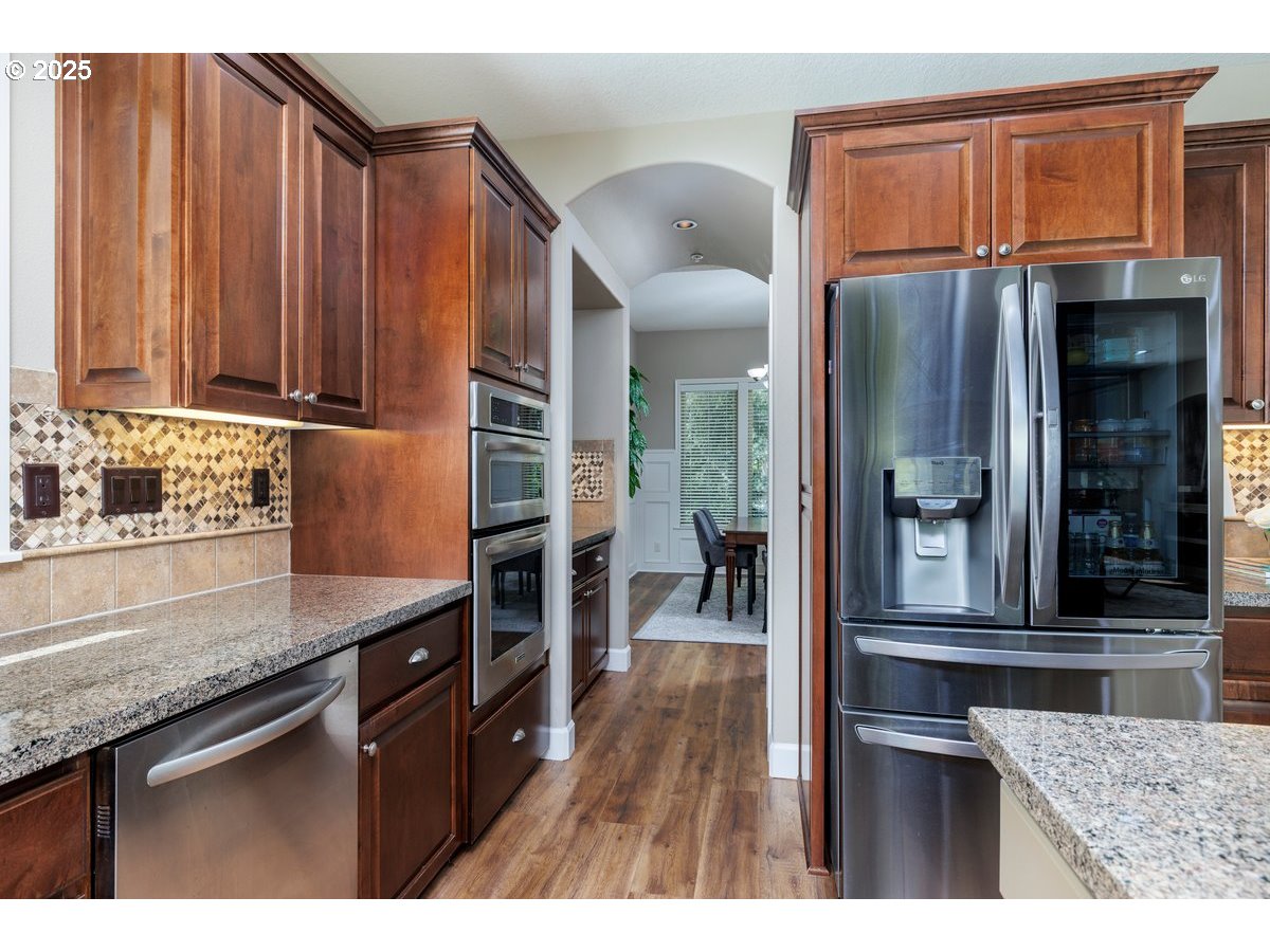 5598 Northwest 135th Avenue Portland, OR 97229 - Photo 15 of 45 a kitchen with stainless steel appliances granite countertop a refrigerator a stove and a sink with wooden cabinets