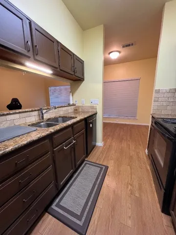 a kitchen with granite countertop stainless steel appliances a sink stove top oven and cabinets