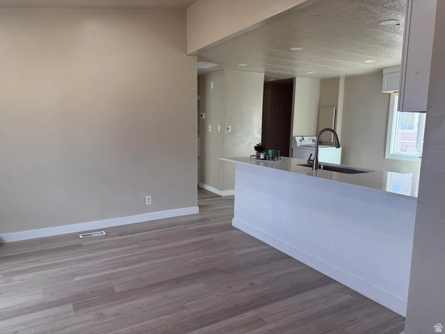 446 Riverside Drive, Unit 24 Wellington, UT 84542 - Photo 5 of 14 Kitchen with white cabinets, light wood finished floors, light stone countertops, a peninsula, and washer / dryer