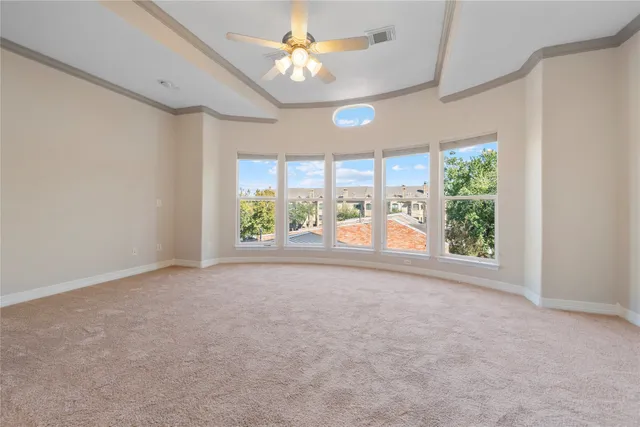 an empty room with chandelier fan and windows