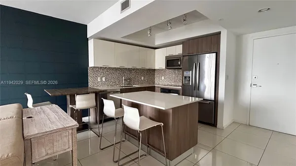 a kitchen with a sink a refrigerator and chairs