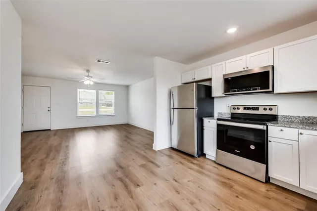 a kitchen with granite countertop a refrigerator and a stove top oven