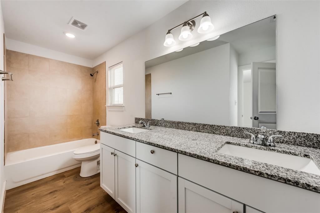 126 Lynn Court, Unit 100 Decatur, TX 76234 - Photo 20 of 20 a bathroom with a granite countertop sink a toilet a mirror and shower