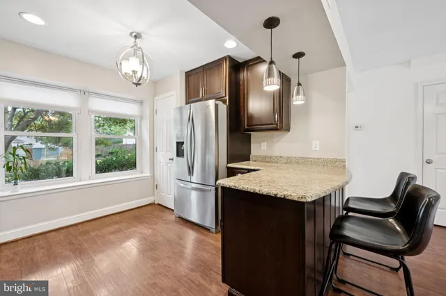 a kitchen with granite countertop a table chairs a refrigerator and a chandelier