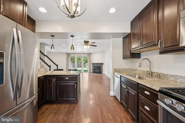 a kitchen with stainless steel appliances granite countertop a refrigerator a sink dishwasher a stove and white countertops with wooden floor