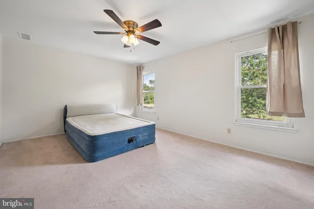 an empty room with windows and ceiling fan
