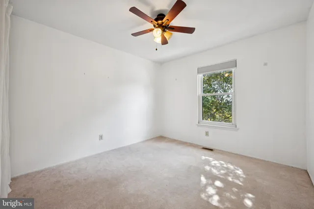 an empty room with a window and a fan