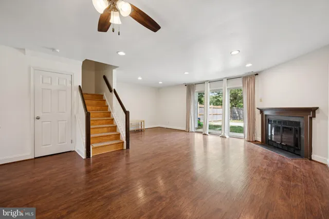 an empty room with wooden floor fireplace and windows