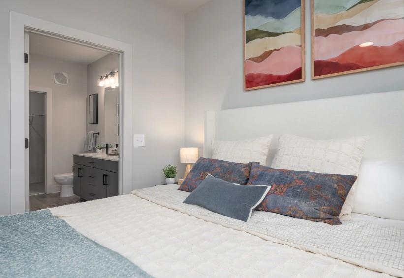 1400 Laurel Crossing Parkway Northeast, Unit 1105 Buford, GA 30519 - Photo 8 of 33 a bedroom with a large bed and chandelier