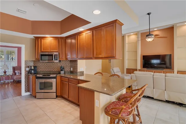 a kitchen with stainless steel appliances granite countertop a stove top oven a sink dishwasher a dining table and chairs with wooden floor