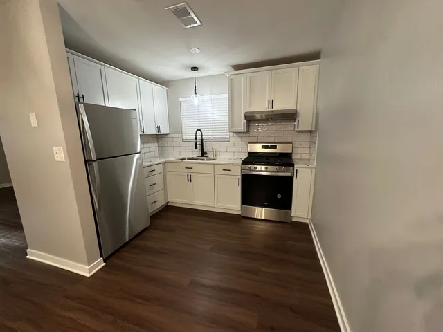 a kitchen with a refrigerator a stove top oven and cabinets