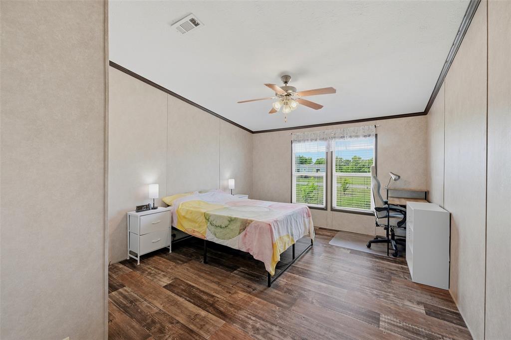 1113 Caroline Court Howe, TX 75459 - Photo 20 of 32 a spacious bedroom with a bed a table and a chandelier