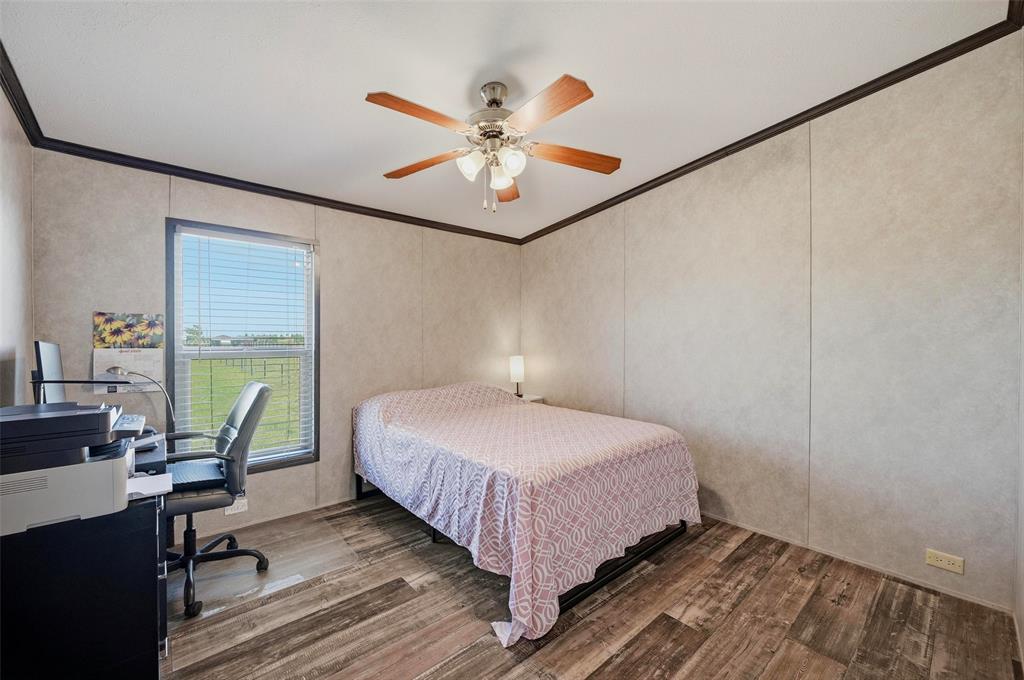 1113 Caroline Court Howe, TX 75459 - Photo 22 of 32 a bedroom with a bed a desk and chair with wooden floor
