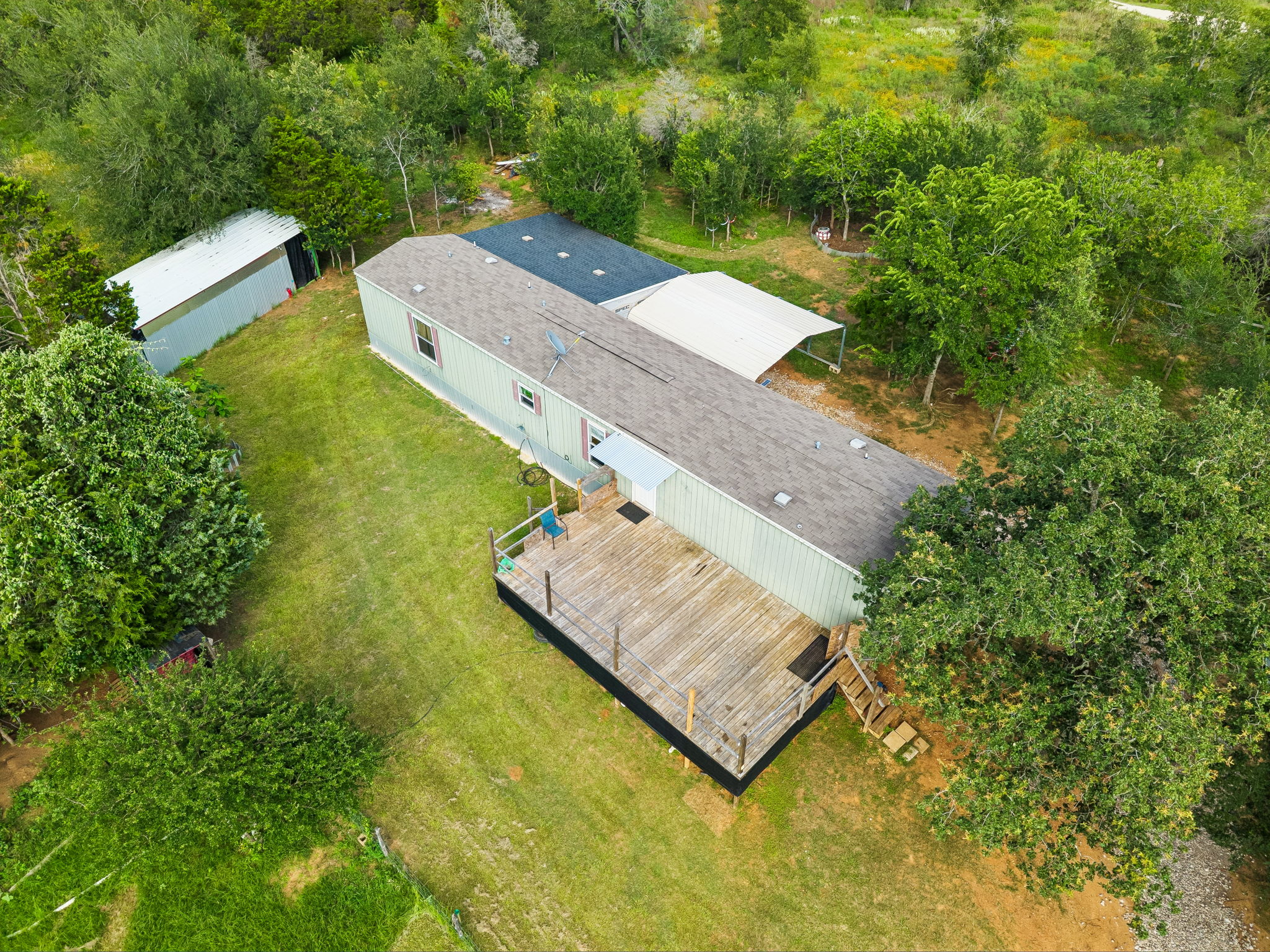 253 North County Line Road, Unit C Elgin, TX 78621 - Photo 30 of 39 An aerial perspective reveals a residence nestled amidst natural tree lines, featuring a broad outdoor deck for leisure.