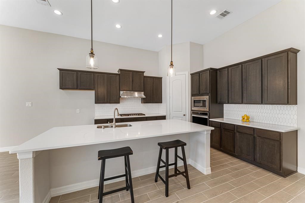 2311 Jitterbug Lane Katy, TX 77493 - Photo 6 of 25 a kitchen with stainless steel appliances a stove a sink a microwave a refrigerator and white cabinets with wooden floor