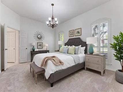 a spacious bedroom with a bed chandelier and window