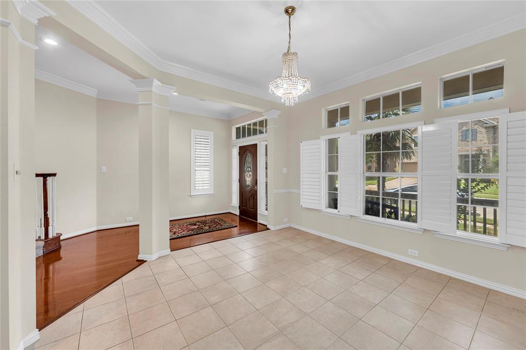 3920 Autumn Lane Bedford, TX 76021 - Photo 7 of 36 Entry area featuring a prominent chandelier, tile flooring, and multiple windows with plantation shutters