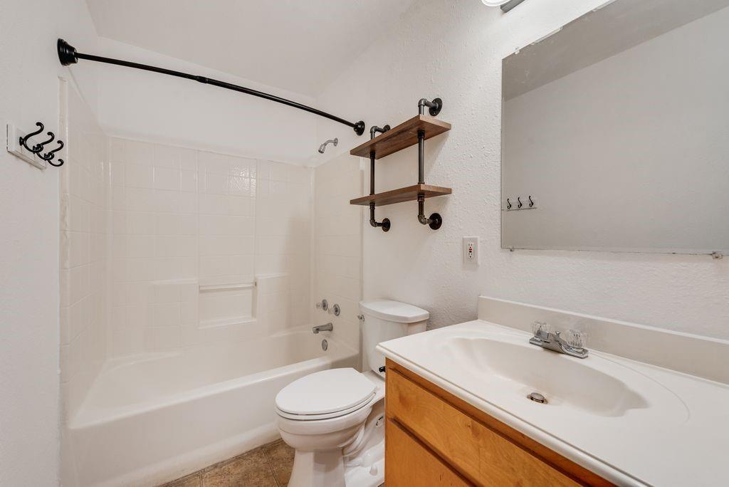 301 Lipscomb Street Cleburne, TX 76031 - Photo 11 of 21 Bathroom featuring vanity, shower combination, and a textured wall