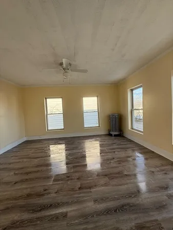 a view of empty room with window and wooden floor