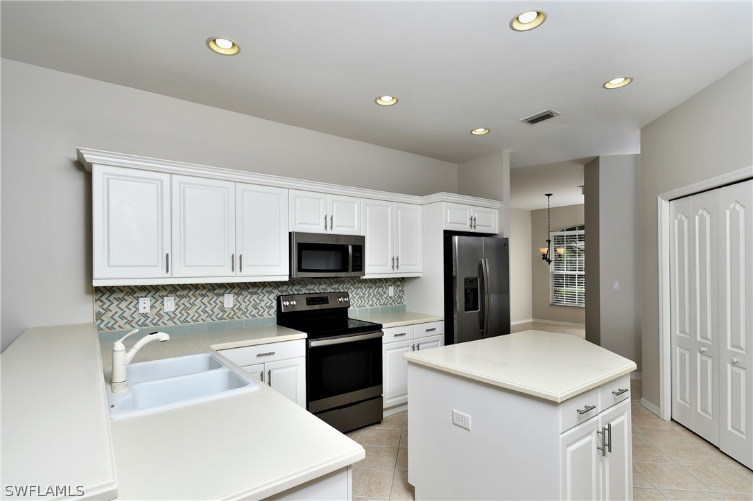 4612 Fairloop Run Lehigh Acres, FL 33973 - Photo 13 of 35 a kitchen with a refrigerator a sink a stove and cabinets