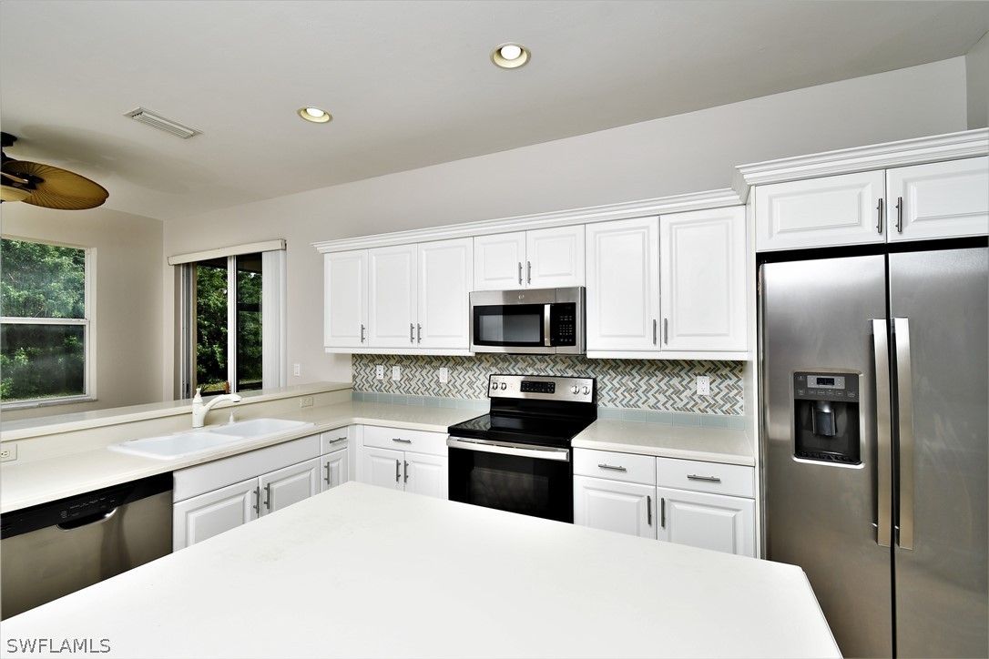 4612 Fairloop Run Lehigh Acres, FL 33973 - Photo 14 of 35 a kitchen with stainless steel appliances a refrigerator stove microwave and sink