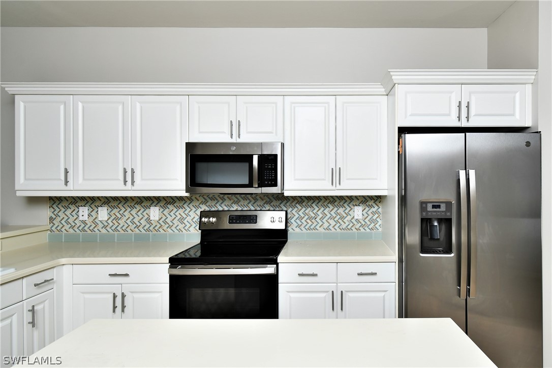 4612 Fairloop Run Lehigh Acres, FL 33973 - Photo 16 of 35 a kitchen with white cabinets and stainless steel appliances