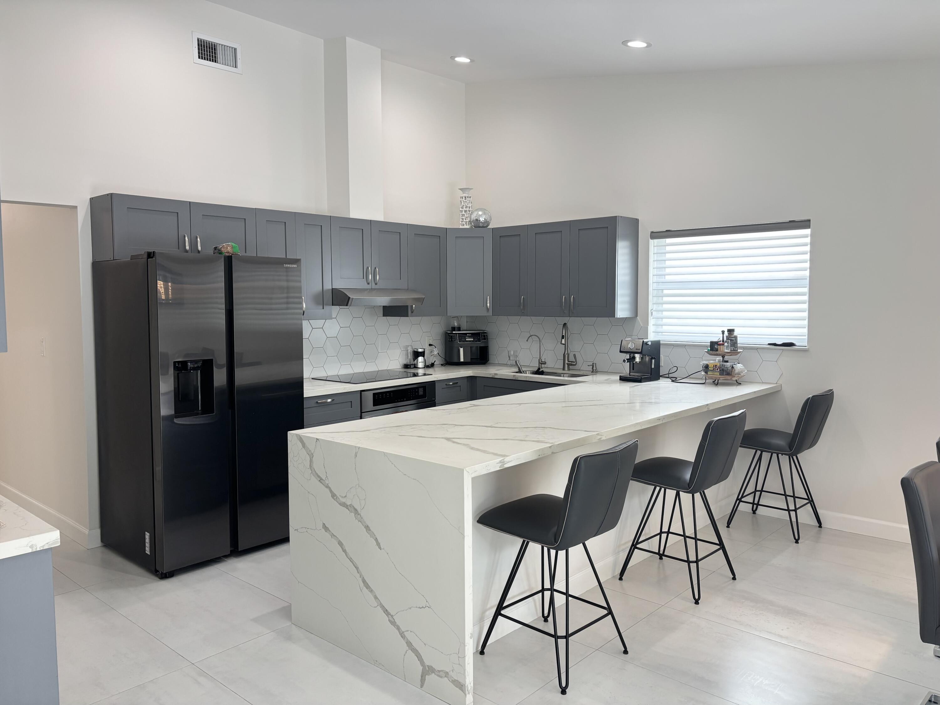 330 Sandalwood Lane Boca Raton, FL 33487 - Photo 2 of 23 a kitchen with stainless steel appliances a table chairs refrigerator and microwave